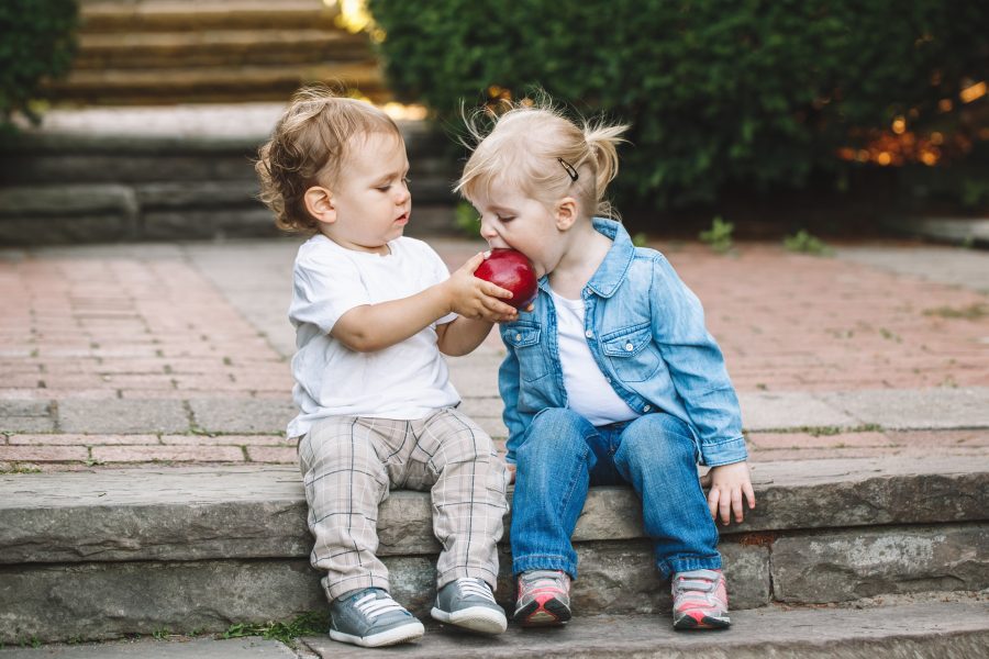 Two kids sharing an apple